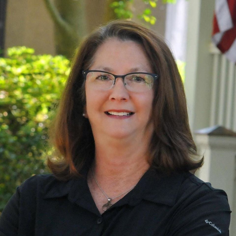 Portrait of Miriam Mace in front of foliage.