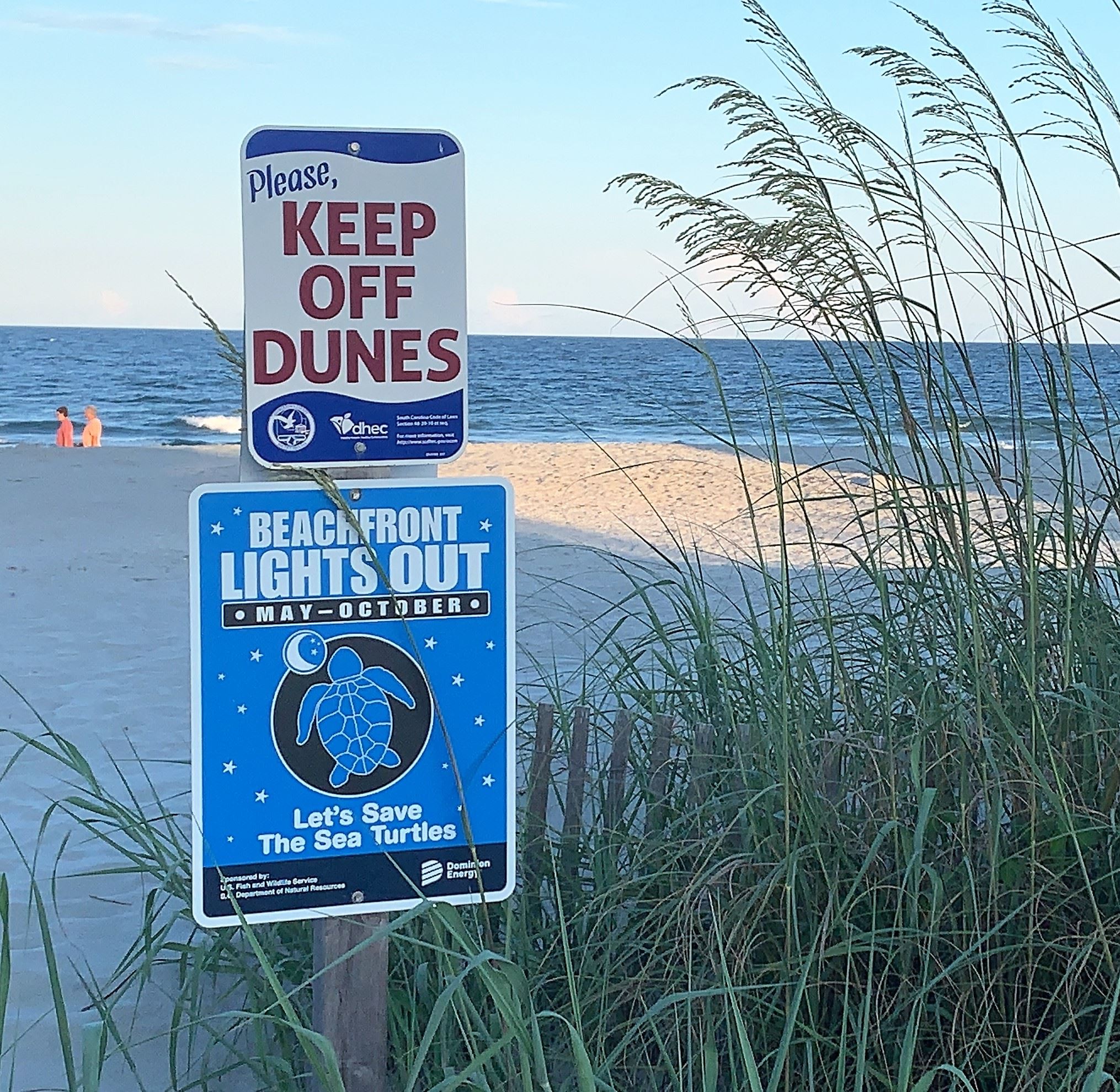 A sign on the beach instructs people to keep off the dunes and keep beach front lights out. 