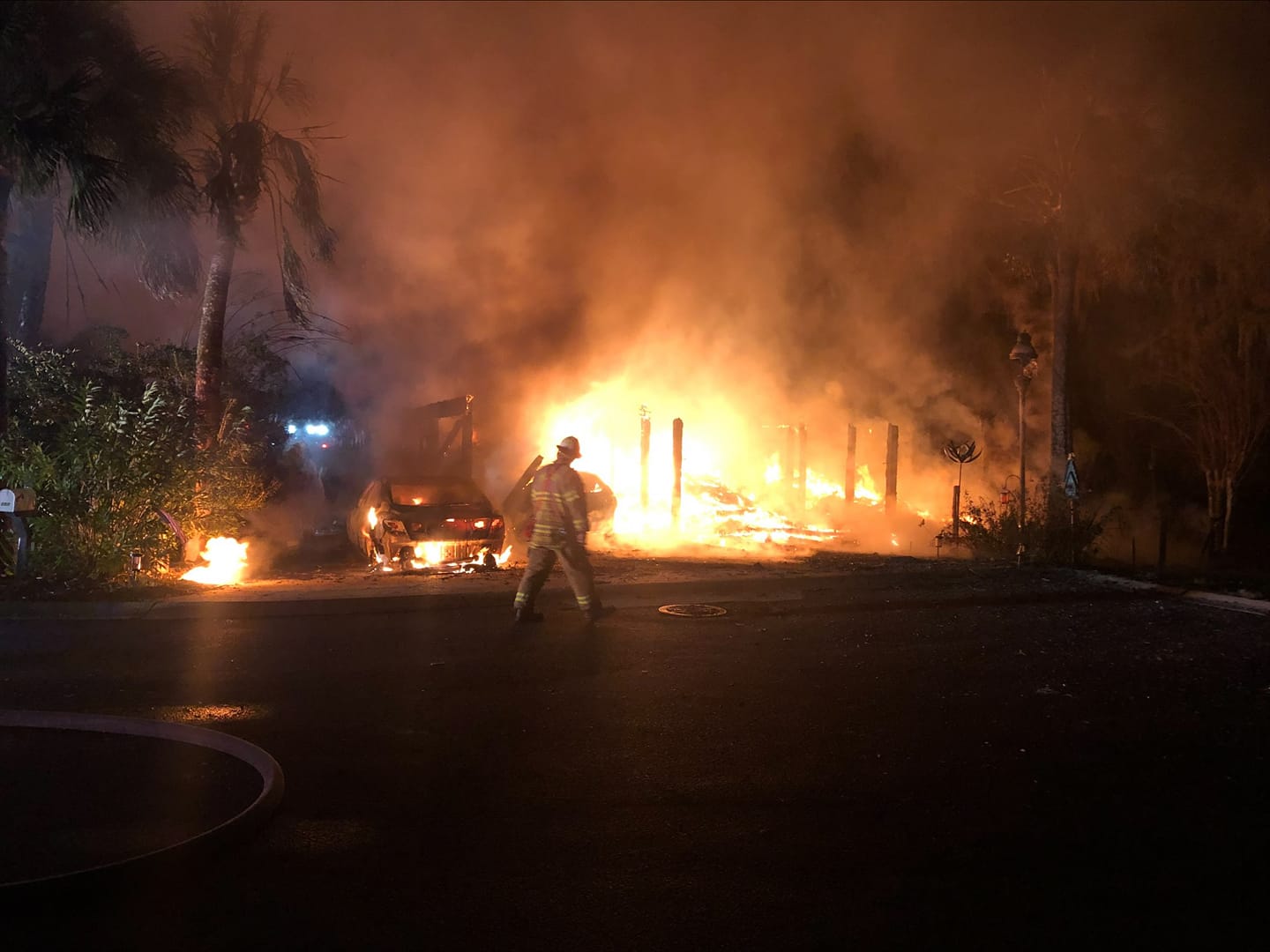Firefighter walking in front of a fully involved house fire