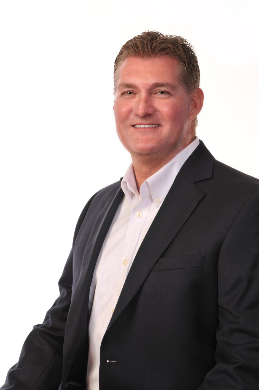 Picture of a man, smiling, wearing a suit.