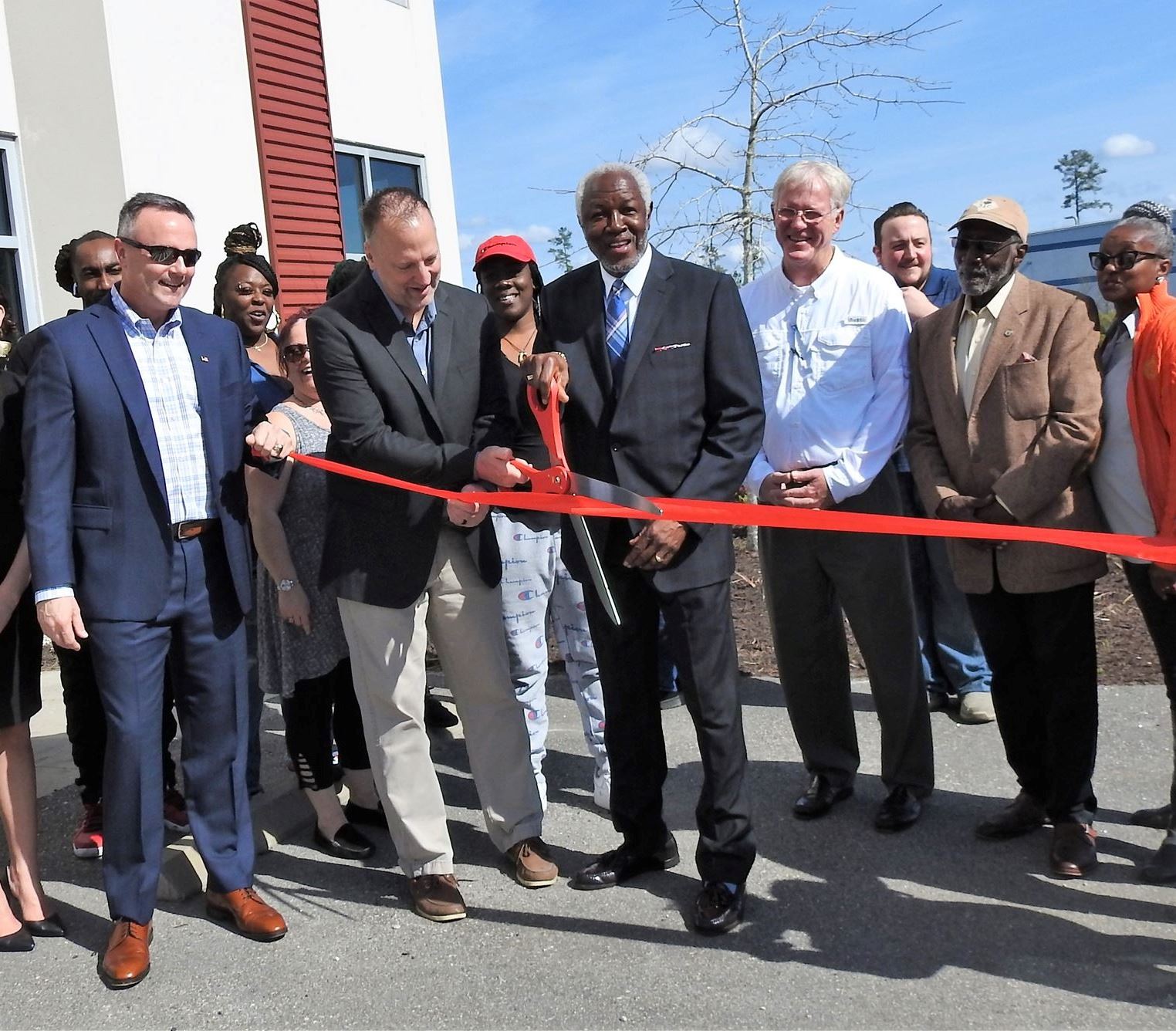 Attendees cutting a red ribbon in front of the new Wingits building