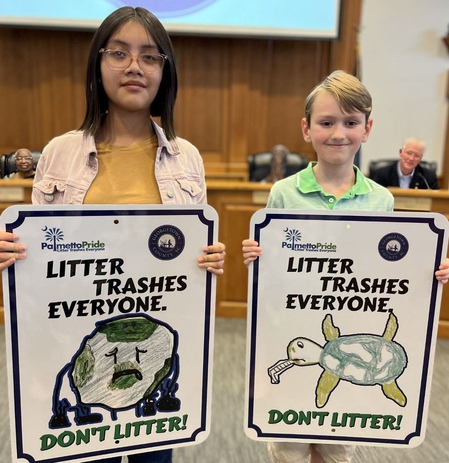 Students holding signs featuring their winning artwork