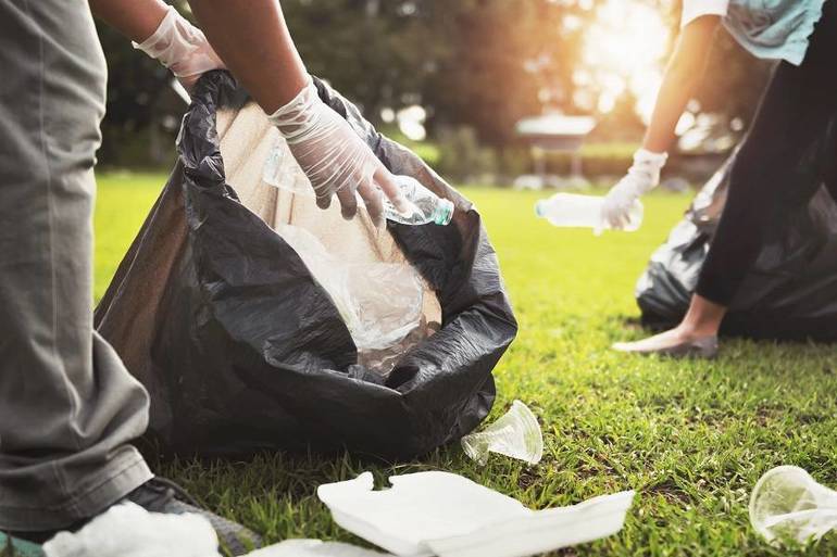 Two people putting litter into trash bags.