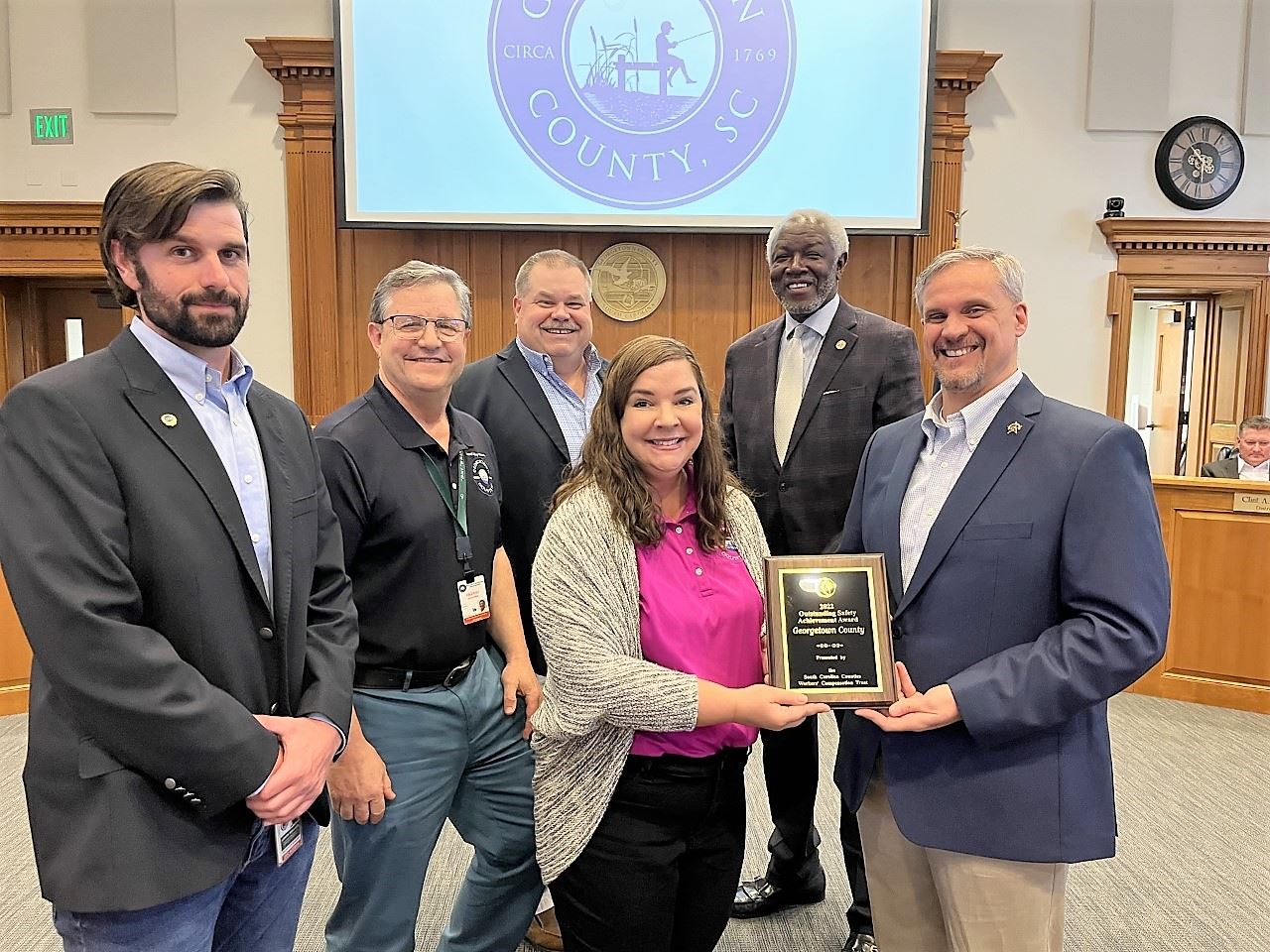 County employees pose with an award plaque in Council Chambers