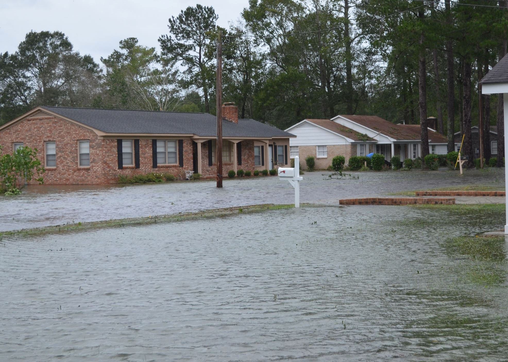 A community of brick homes with flooded yards and streets