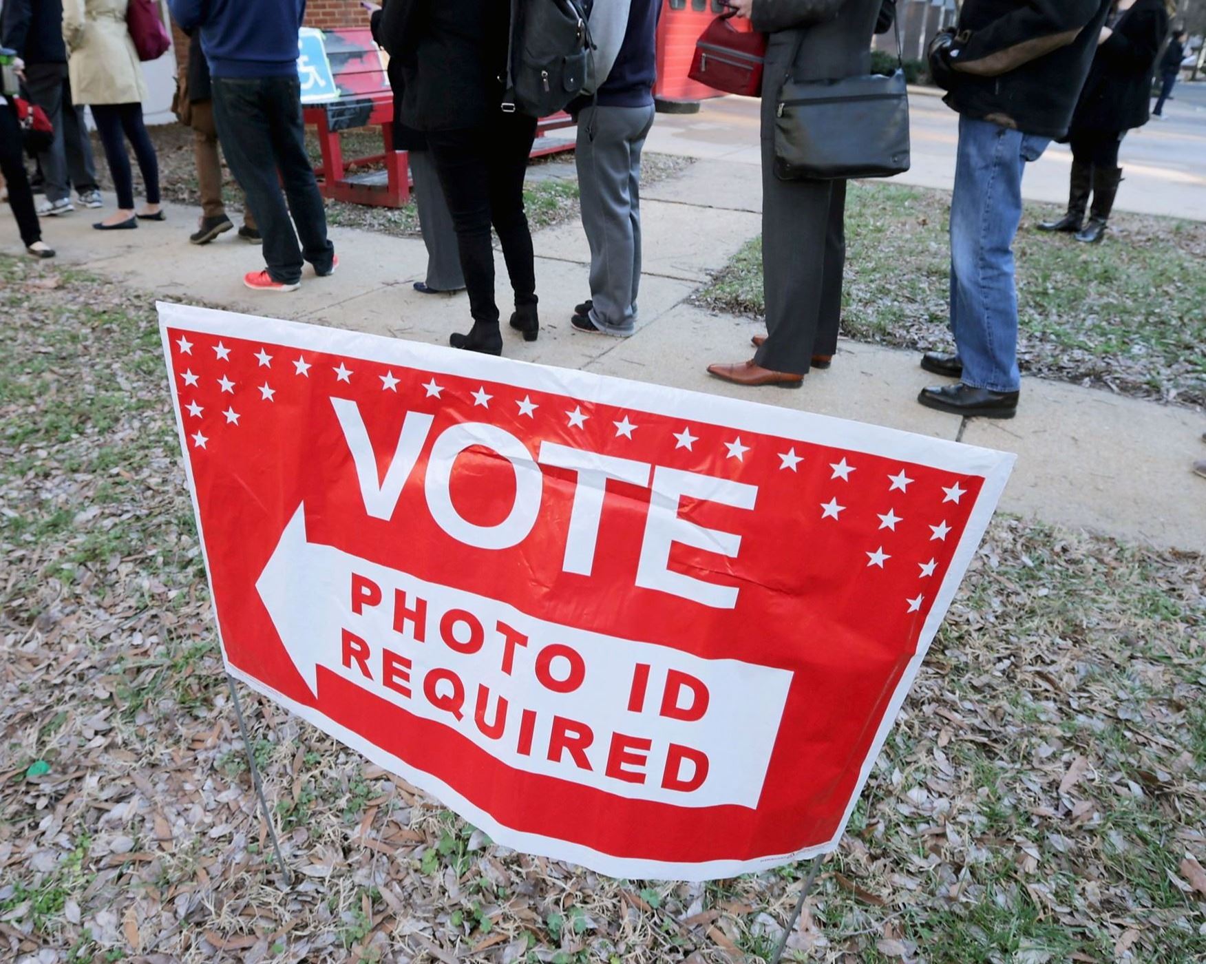 People lined up outside a polling place in front of a sign saying 