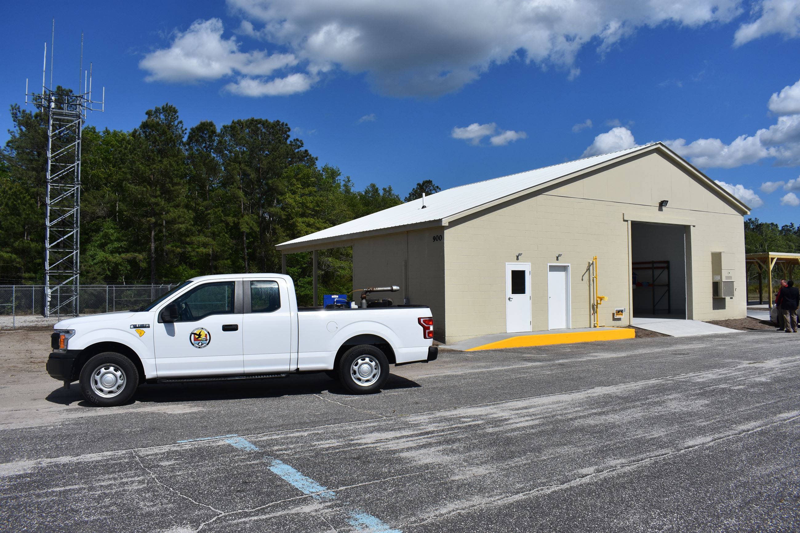 A mosquito control truck parked in front of a small block building.