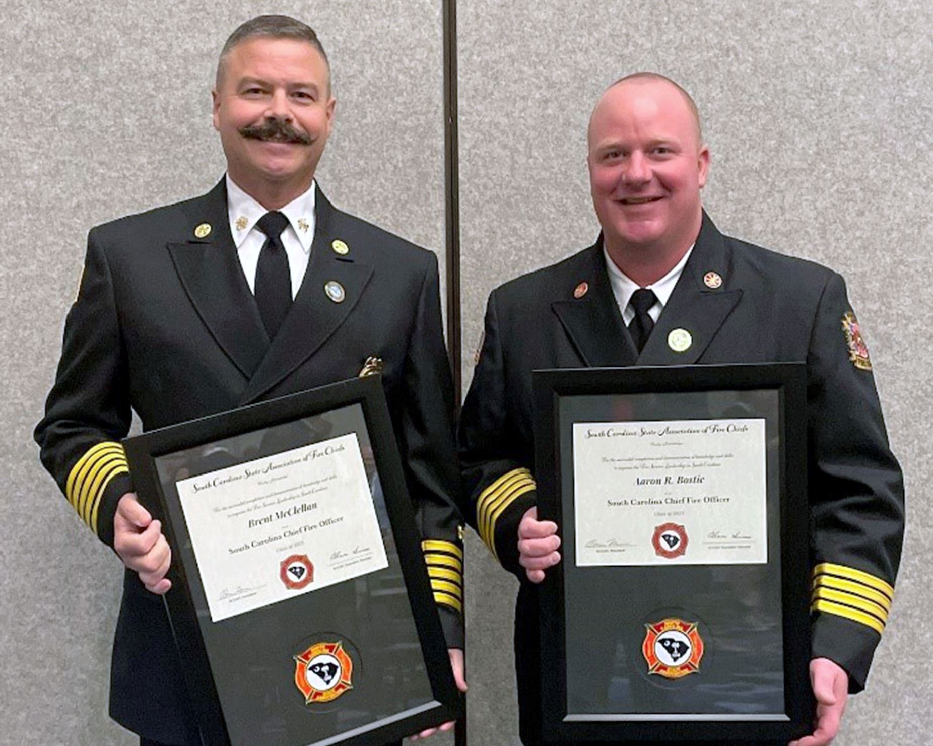 Brent McClellan, left, and Aaron Bostic stand side by side holding their framed certificates.