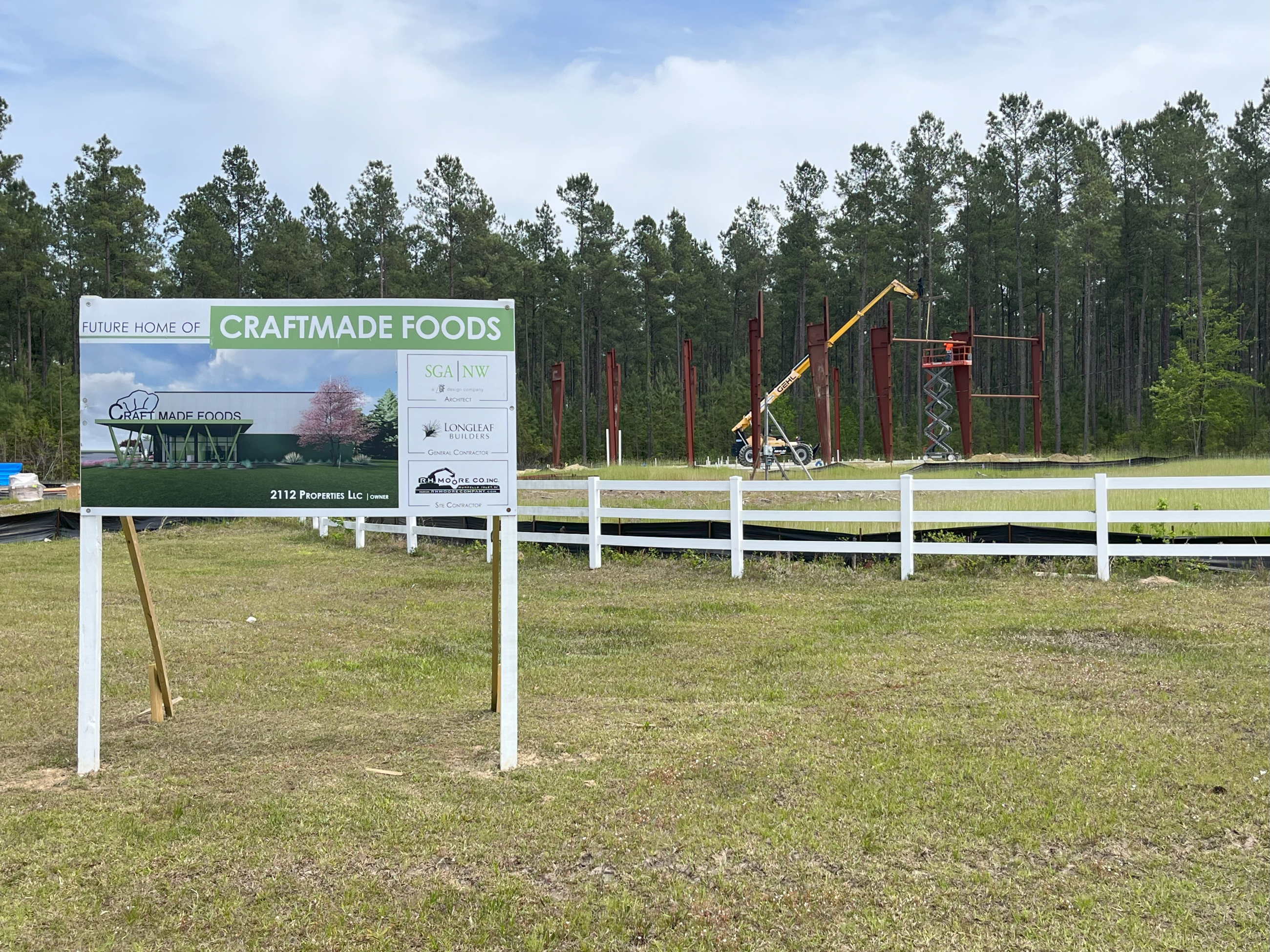 A sign in front of the steel frame of a building programs Kraftmade Foods is coming soon
