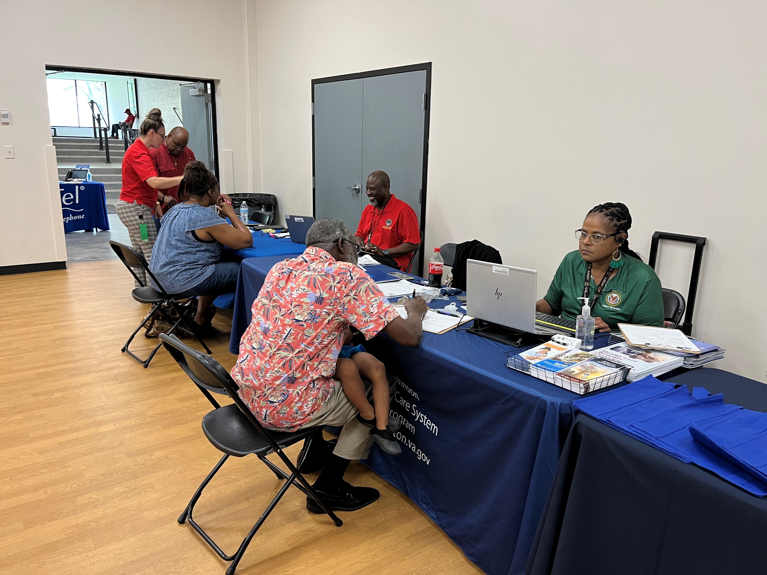 Tables are lined up with people filling out forms on one side and staff offering assistance