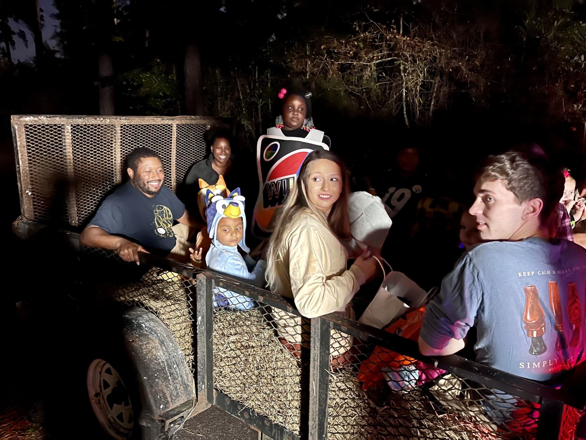 families of various races enjoying a night-time hayride through the forest