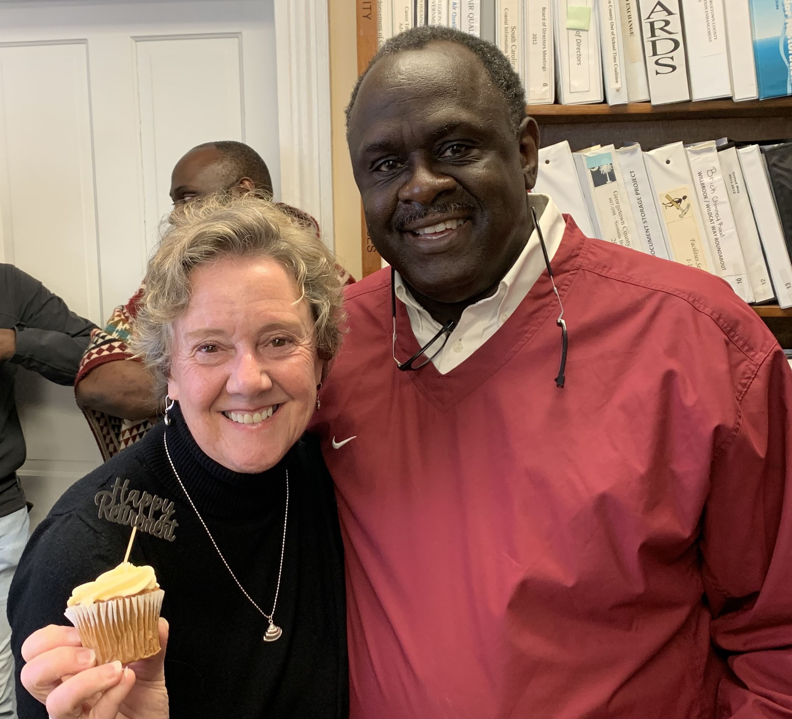 Janet Fricke and Ray Funnye at Janet's retirement party. She is holding a cupcake.