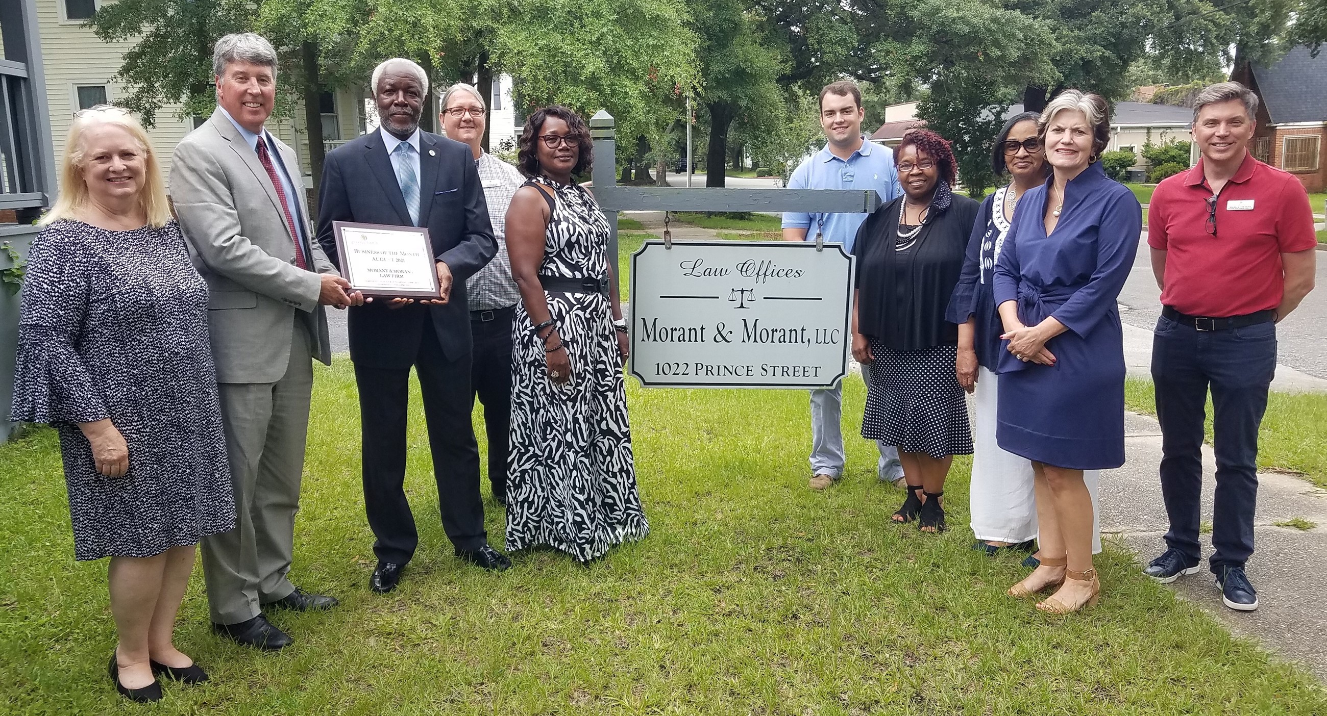 A group of people standing in a yard, accepting an award.