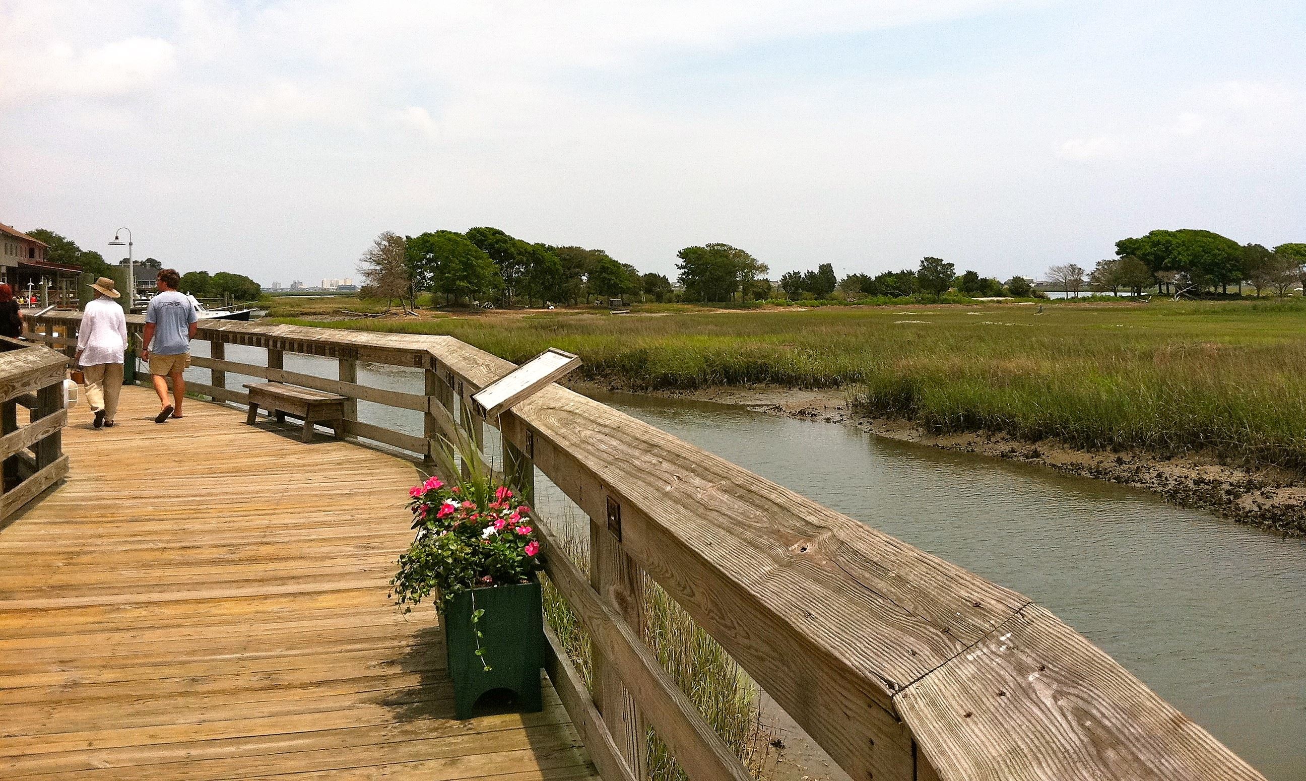 People walk along the wooden boardwalk known as the Murrells Inlet MarshWalk